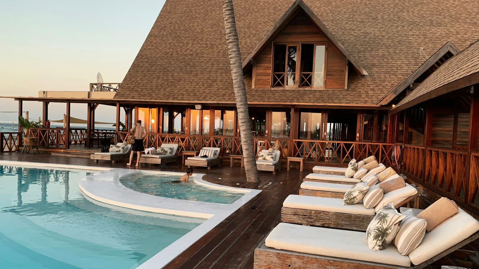 A swimming pool terrace at dusk beside timber decking